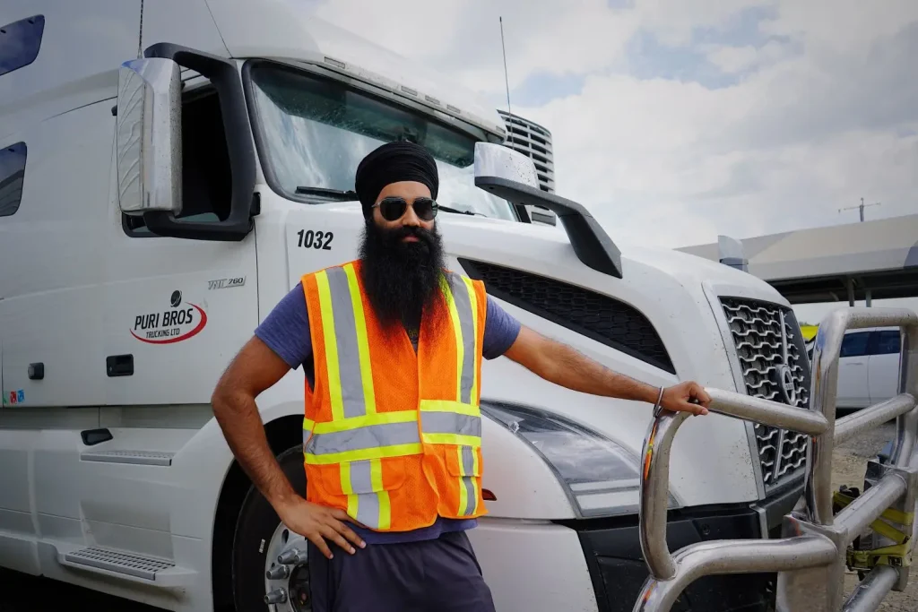 Commercial truck driver in a safety vest beside his vehicle